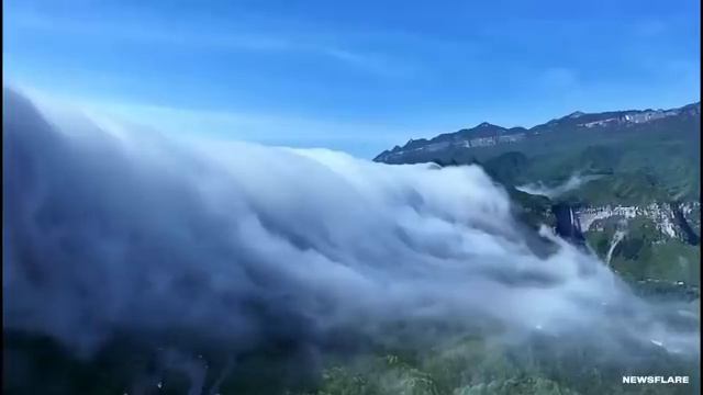 Nappe de nuages se déversant par-dessus une montagne comme une cascade