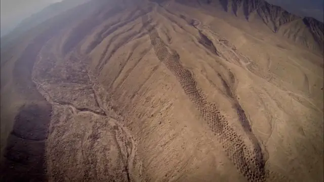 Vue aérienne de la mystérieuse « Bande de Trous » au Pérou, montrant des milliers de cavités alignées sur le flanc d'une montagne.