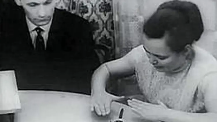 Une femme participant à une expérience de télékinésie en laboratoire, se concentrant sur un objet sous cloche.