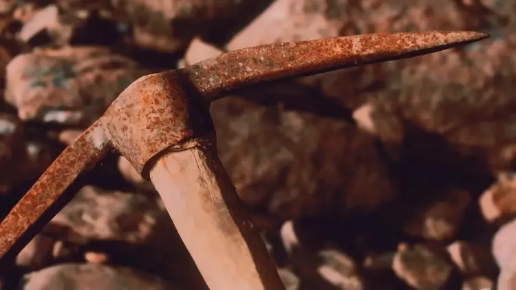 Gros plan sur un vieil outil de type pioche, illustrant la théorie des outils en cuivre.