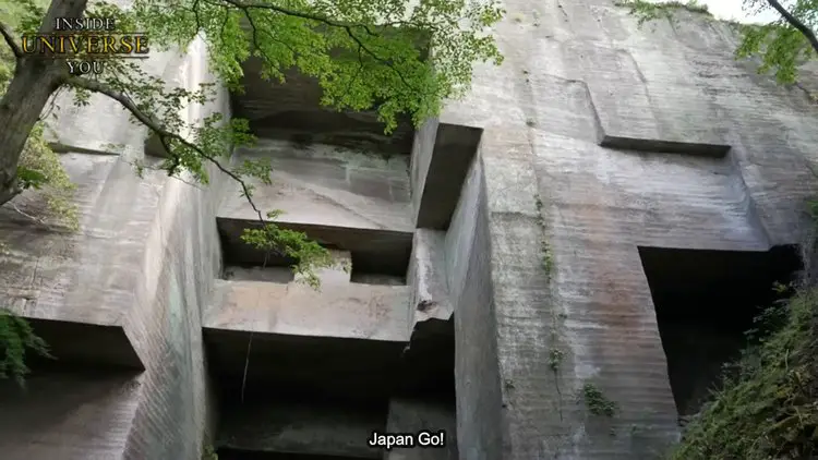 Vue rapprochée d'une paroi de pierre taillée avec des marques régulières.