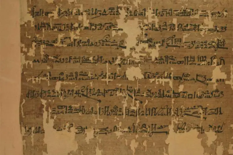 Gros plan sur l'ancien papyrus égyptien Anastasi I, avec une écriture hiératique en encre noire sur un fond brun clair patiné.