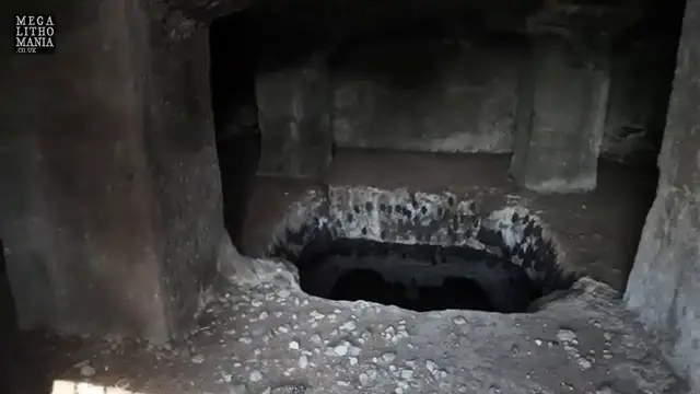Gros plan sur une cavité profonde et sombre dans le sol, témoignant des mystérieux espaces creusés dans la structure rocheuse.