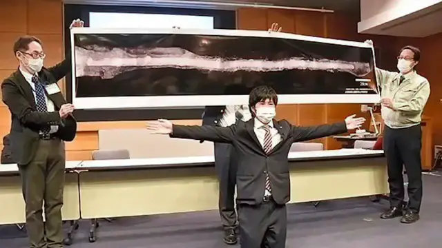Des experts présentent une photographie de l'épée Dako géante, illustrant sa taille impressionnante de 2,3 mètres.