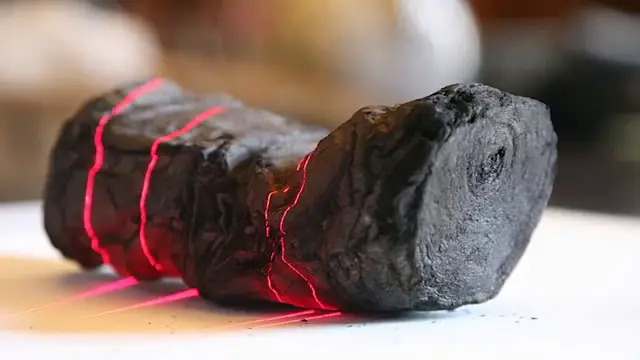 Gros plan sur un rouleau d'Herculanum carbonisé, scanné par des lasers rouges pour tenter de le lire sans l'ouvrir.