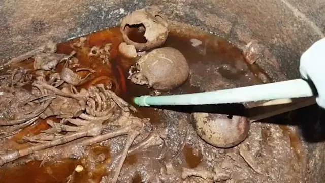 Vue à l'intérieur du sarcophage noir d'Alexandrie, montrant des squelettes immergés dans des eaux usées rougeâtres.